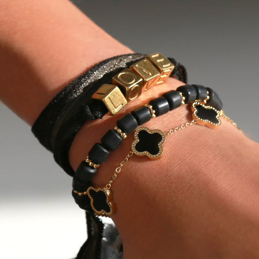 Black and gold themed bracelets worn together