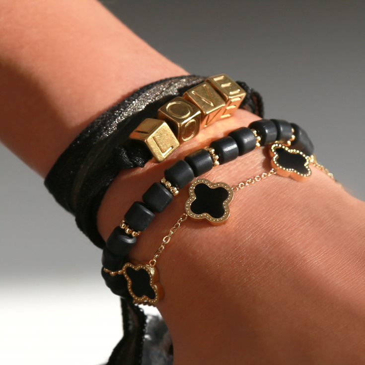 Black and gold themed bracelets worn together 